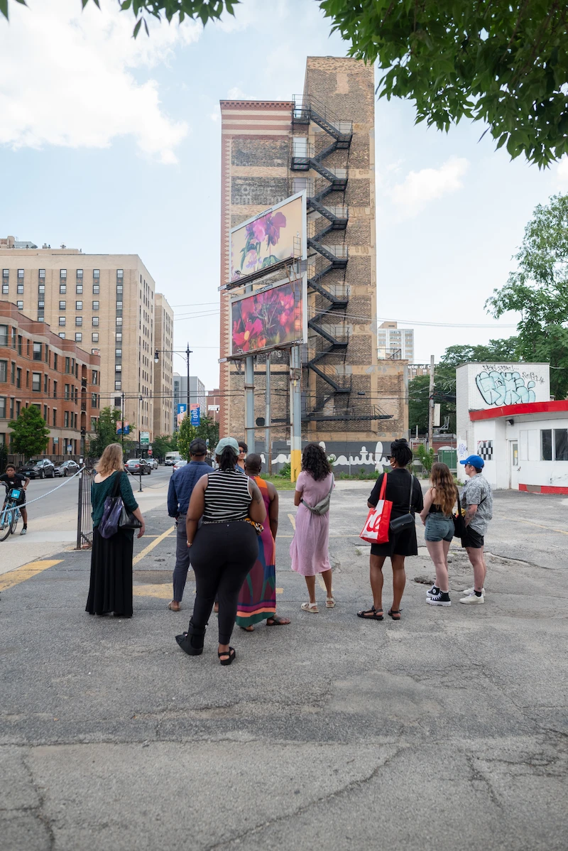 People standing in the streets of chicago admiring art on a building